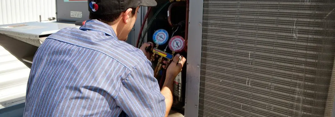 HVAC technician servicing a condenser unit in West Loch Estate